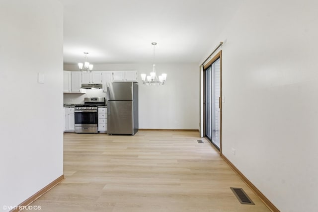 kitchen with stainless steel appliances, a chandelier, white cabinets, under cabinet range hood, and light wood-style flooring