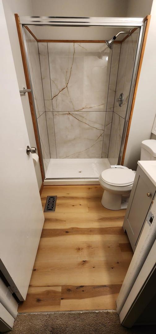 218 Oak Knoll Ct Unit D1, Schaumburg, IL 60193 - bathroom with a shower stall, toilet, wood finished floors, and vanity