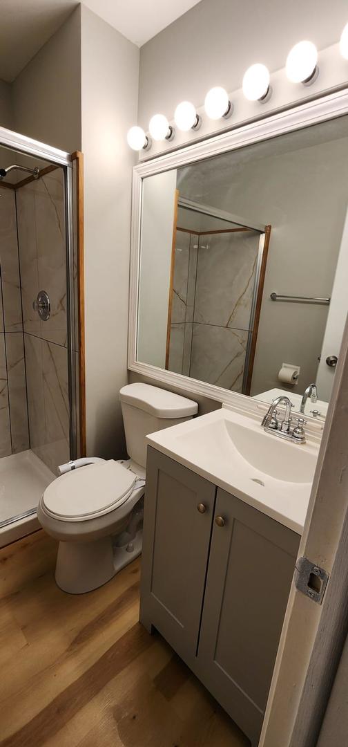 218 Oak Knoll Ct Unit D1, Schaumburg, IL 60193 - full bath featuring wood finished floors, a shower stall, toilet, and vanity
