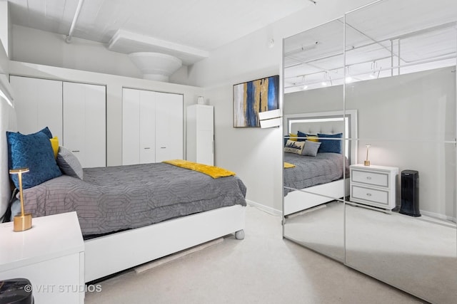 bedroom featuring carpet floors, multiple closets, and baseboards