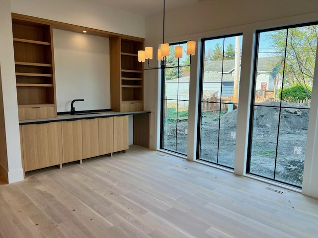 unfurnished dining area with light wood finished floors, visible vents, and a chandelier