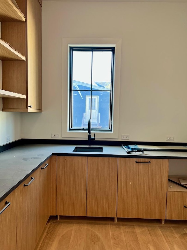 kitchen featuring open shelves, light wood-style floors, and a sink
