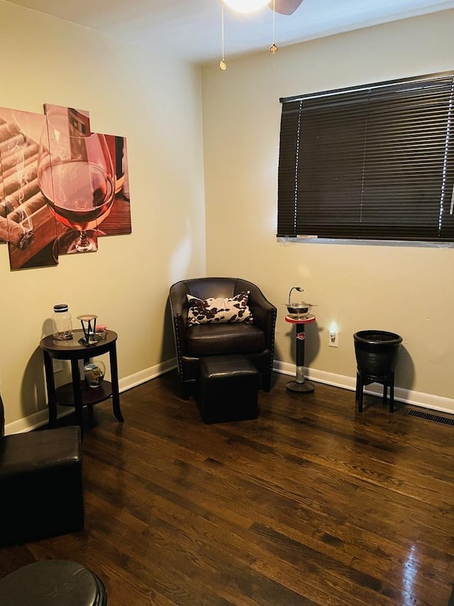 living area featuring wood finished floors, ceiling fan, visible vents, and baseboards