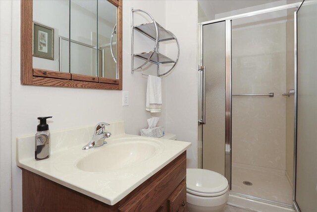 bathroom with a stall shower, toilet, and vanity