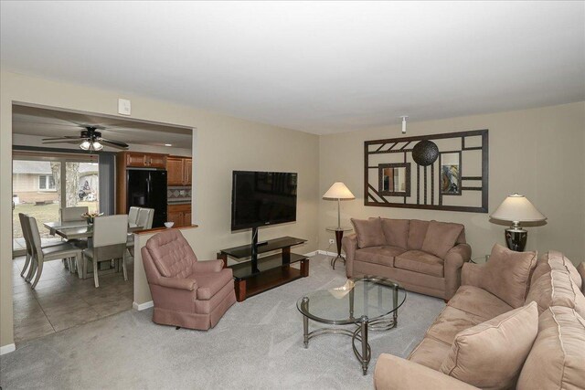 living room with a ceiling fan, light carpet, and baseboards