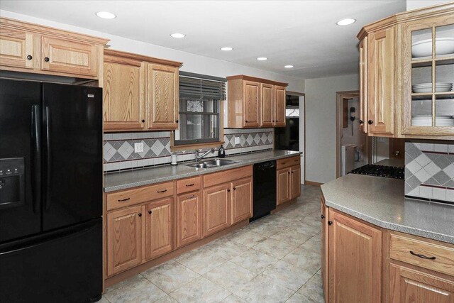 kitchen featuring recessed lighting, glass insert cabinets, decorative backsplash, black appliances, and a sink