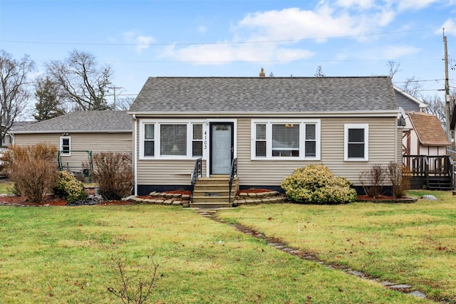 view of front facade with a deck, a shingled roof, and a front lawn