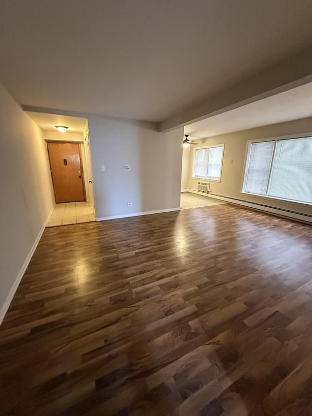spare room featuring a baseboard radiator, wood finished floors, a ceiling fan, and baseboards