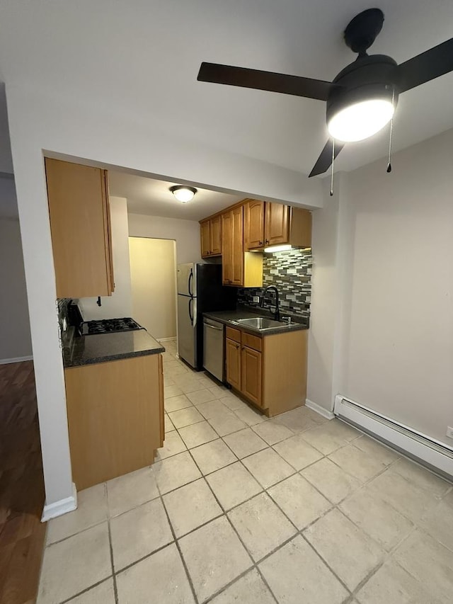 kitchen featuring dark countertops, tasteful backsplash, a sink, ceiling fan, and appliances with stainless steel finishes