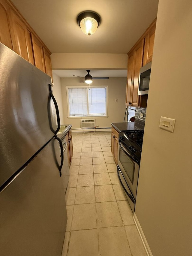 kitchen featuring brown cabinetry, a wall mounted AC, light tile patterned floors, stainless steel appliances, and baseboards