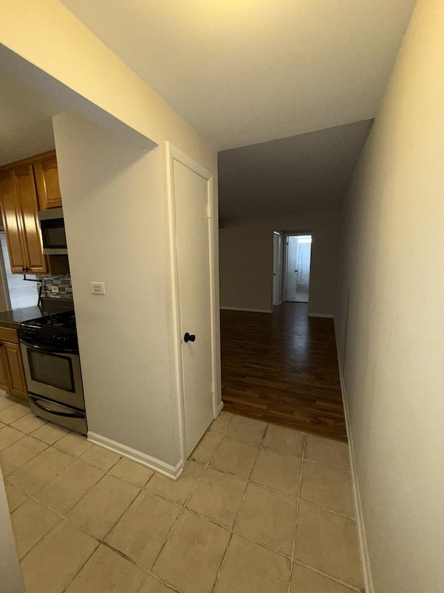 hall with baseboards and light tile patterned floors