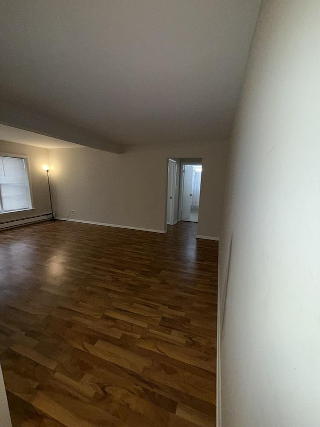 empty room featuring baseboards, a baseboard radiator, and dark wood-style flooring