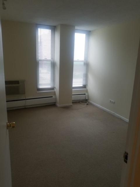 5401 S Hyde Park Blvd Unit 705, Chicago, IL 60615 - carpeted empty room featuring a baseboard radiator, an AC wall unit, and baseboards