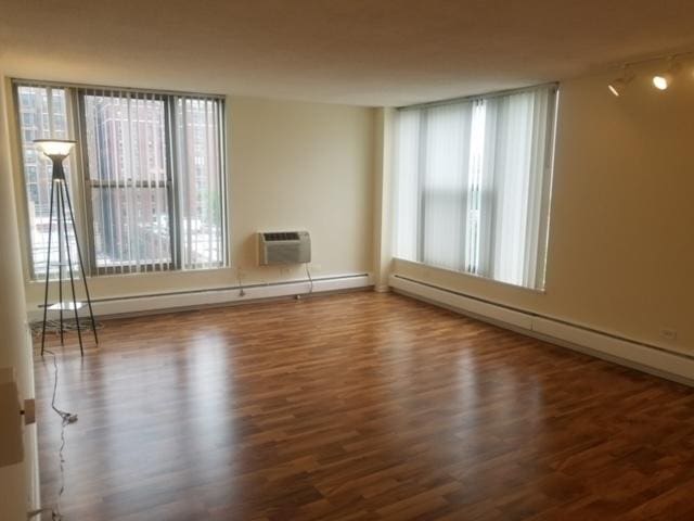 5401 S Hyde Park Blvd Unit 705, Chicago, IL 60615 - empty room with a wall mounted air conditioner, a baseboard radiator, and wood finished floors
