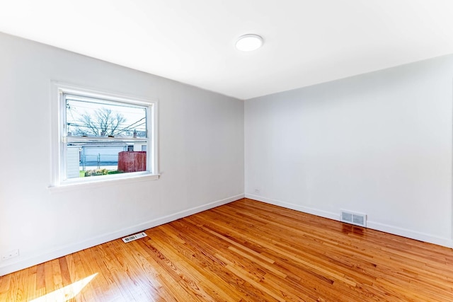 unfurnished room featuring light wood-type flooring, visible vents, and baseboards