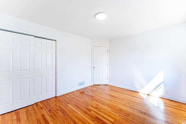 unfurnished bedroom with light wood-style flooring, visible vents, and baseboards