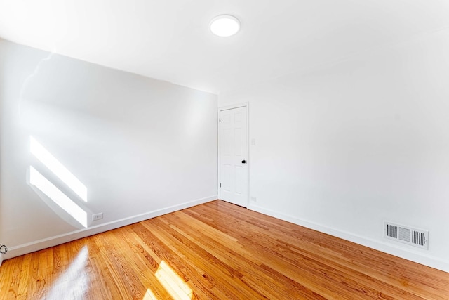 spare room with light wood-style floors, visible vents, and baseboards