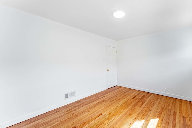empty room featuring baseboards, wood finished floors, and visible vents