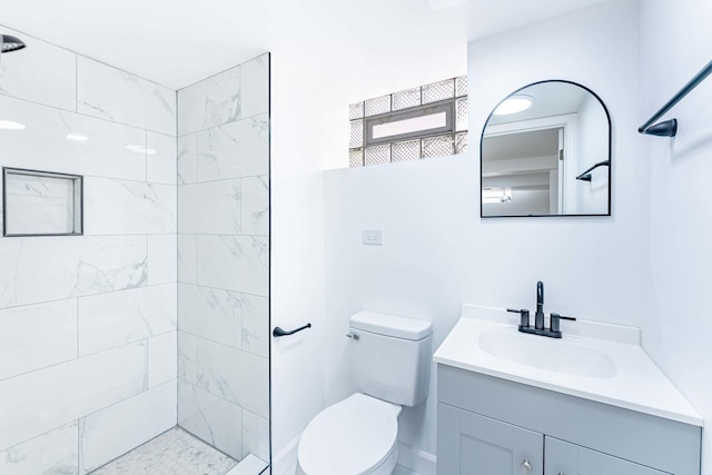 full bath featuring toilet, vanity, and tiled shower