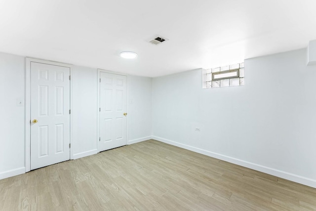 below grade area featuring light wood-type flooring, baseboards, and visible vents