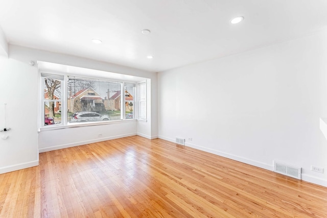 unfurnished room with wood finished floors, visible vents, and baseboards