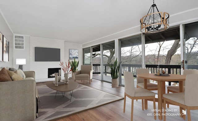 living area with a chandelier, wood finished floors, crown molding, and a fireplace