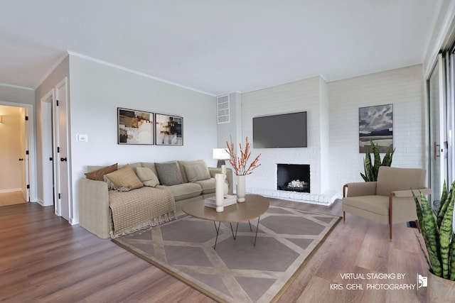 living area with wood finished floors, a fireplace, crown molding, and baseboards