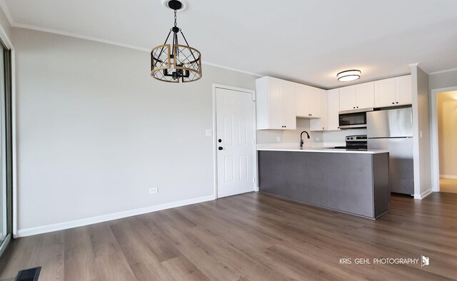 kitchen featuring appliances with stainless steel finishes, crown molding, dark wood finished floors, a chandelier, and light countertops
