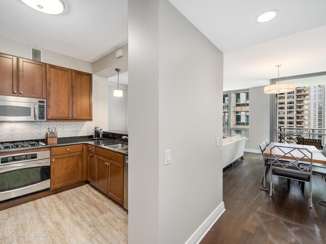 600 N Lake Shore Dr Unit 1802, Chicago, IL 60611 - kitchen with visible vents, dark countertops, brown cabinets, light wood-style flooring, and appliances with stainless steel finishes
