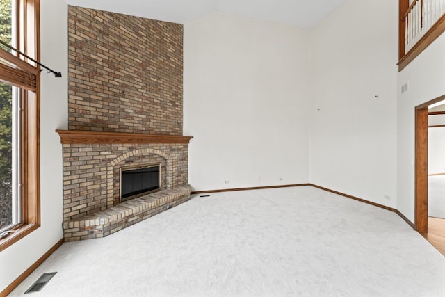 unfurnished living room featuring high vaulted ceiling, a fireplace, baseboards, carpet flooring, and visible vents