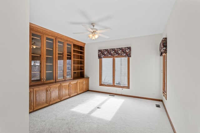 spare room with light colored carpet, baseboards, a ceiling fan, and visible vents