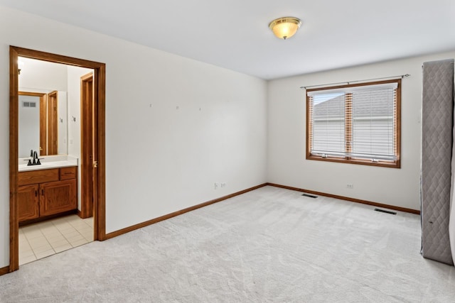 empty room featuring light carpet, baseboards, visible vents, and a sink