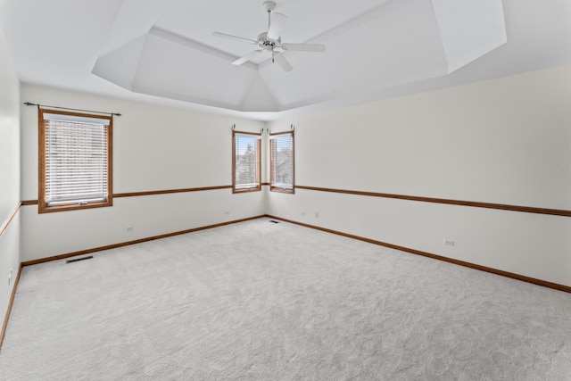 unfurnished room featuring baseboards, visible vents, carpet, a ceiling fan, and a raised ceiling
