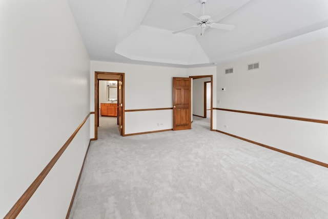 unfurnished room with light colored carpet, ceiling fan, a tray ceiling, and visible vents