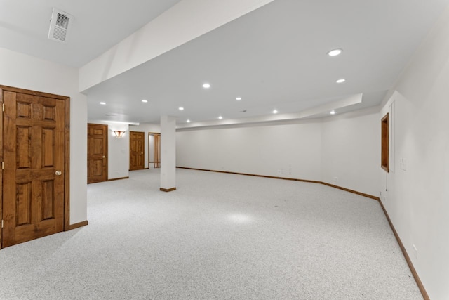 finished below grade area featuring baseboards, visible vents, recessed lighting, and light colored carpet