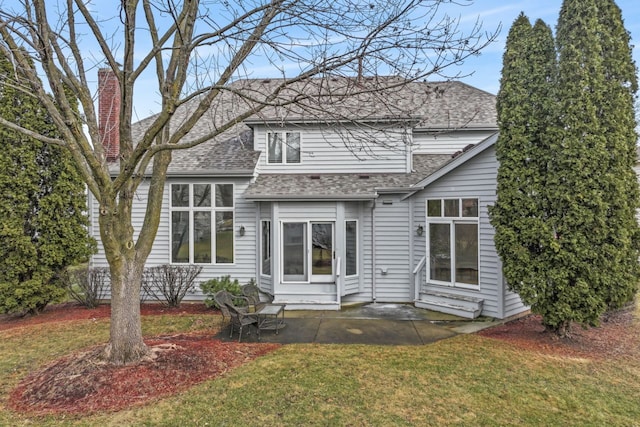 back of house with a patio area, a shingled roof, a chimney, and a yard