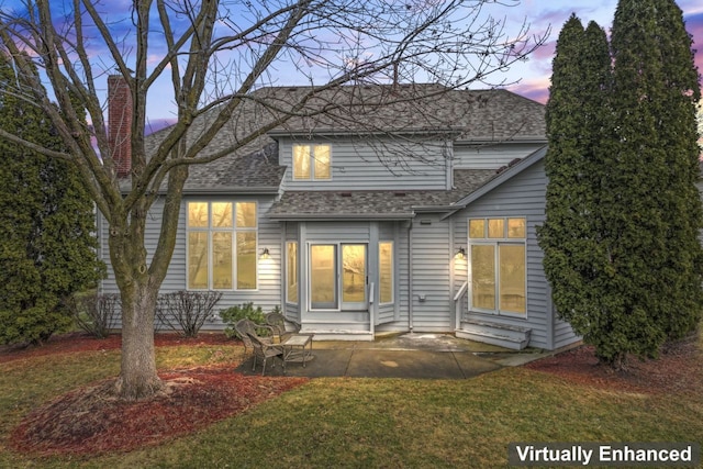 view of front of property featuring a patio, a shingled roof, and a front yard
