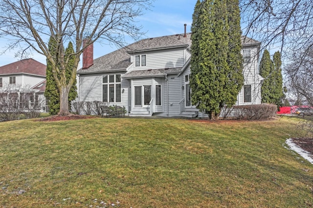 rear view of property featuring a chimney, entry steps, and a yard