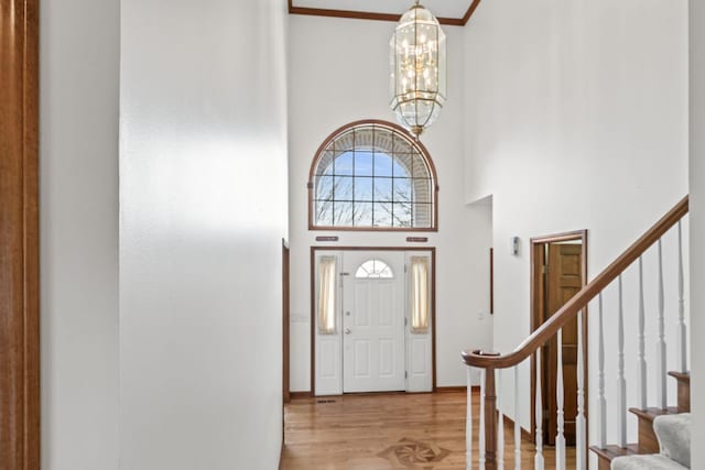 foyer entrance featuring baseboards, a towering ceiling, a chandelier, wood finished floors, and stairway