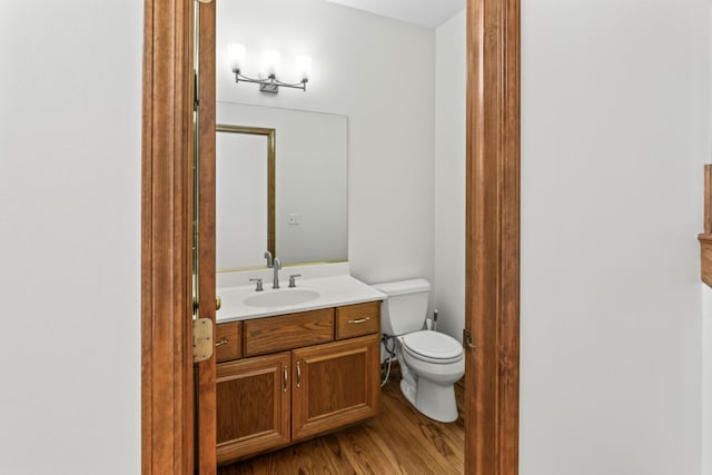 bathroom with wood finished floors, toilet, and vanity