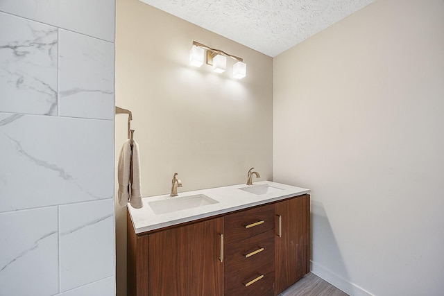 2104 Oakwood Ave, Bloomington, IL 61704 - full bathroom with double vanity, a textured ceiling, baseboards, and a sink