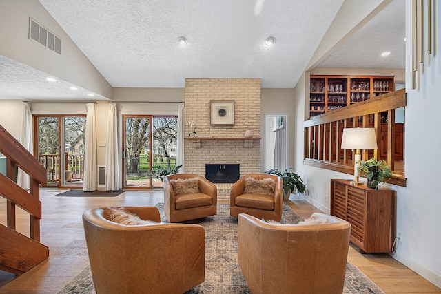 2104 Oakwood Ave, Bloomington, IL 61704 - living room featuring stairs, hardwood / wood-style flooring, a brick fireplace, baseboards, and visible vents