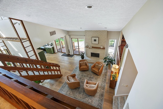 2104 Oakwood Ave, Bloomington, IL 61704 - living room with a textured ceiling, visible vents, a fireplace, wood finished floors, and stairs