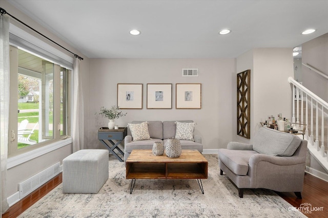 living room with visible vents, wood finished floors, and stairway
