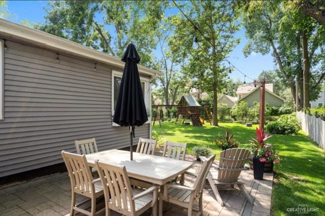 view of patio / terrace featuring a playground, fence, and outdoor dining space