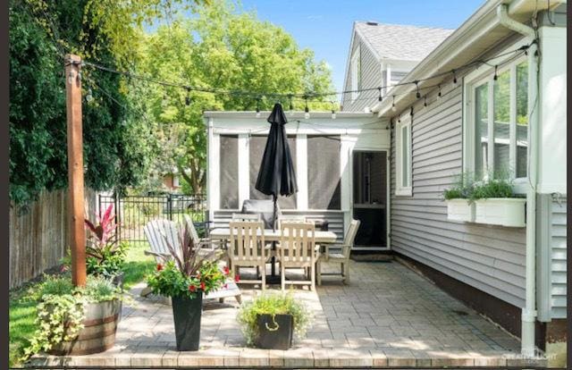 view of patio / terrace featuring fence, outdoor dining area, and a sunroom
