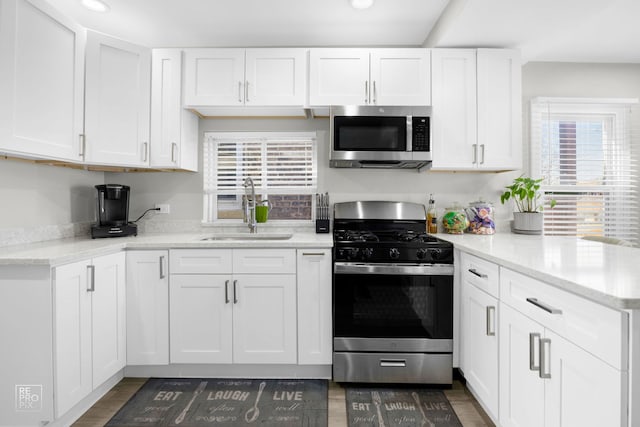 kitchen with a sink, white cabinetry, a peninsula, appliances with stainless steel finishes, and recessed lighting