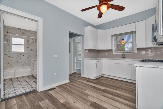 13916 S Dearborn St, Riverdale, IL 60827 - kitchen featuring a ceiling fan, wood finished floors, light countertops, white cabinetry, and visible vents