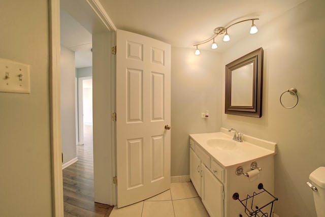 half bathroom with baseboards, vanity, and toilet