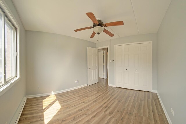 unfurnished bedroom with a baseboard radiator, a closet, ceiling fan, light wood-style flooring, and baseboards